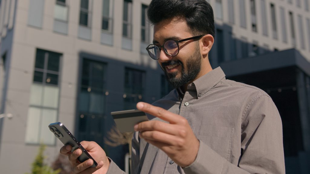 Cliente sostiene una tarjeta bancaria para pagar una compra desde su celular