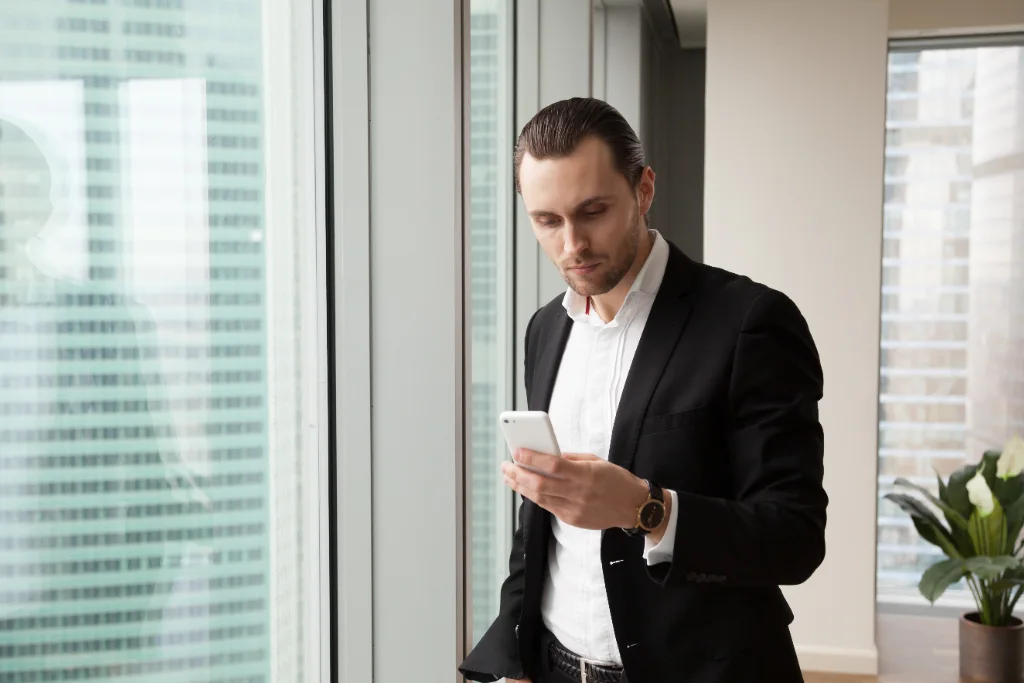 Ejecutivo consultando mensajes SMS en su smartphone en la oficina