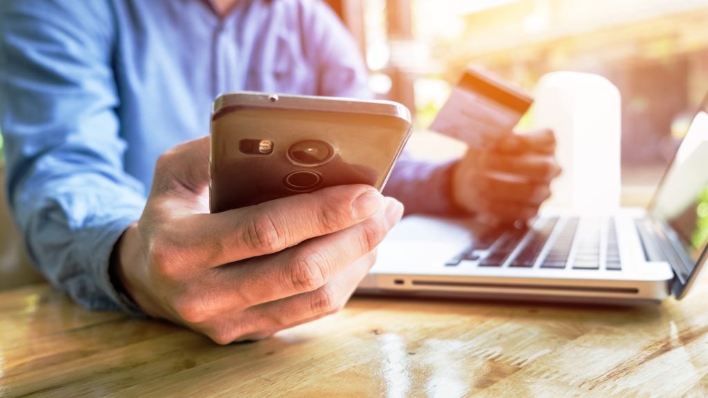 Fintech Hombre con tarjeta en mano ingresa un código de seguridad en su celular