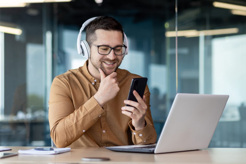 Programador trabaja con su laptop y su teléfono en una oficina
