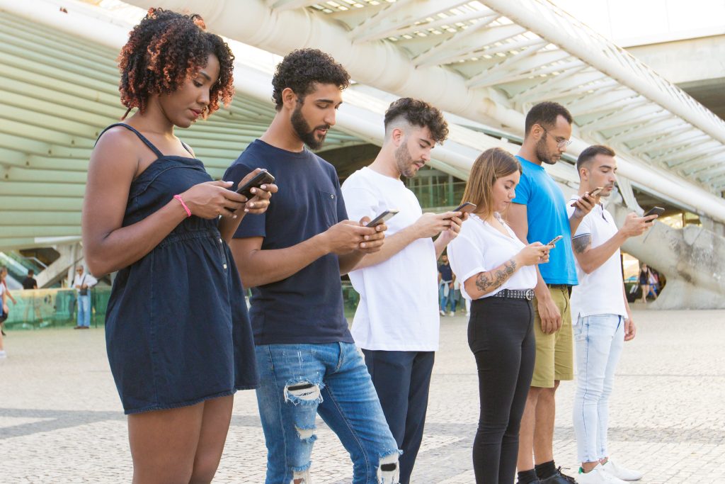 Guía de SMS masivos en México: requisitos legales y buenas prácticas Grupo de personas recibiendo mensajes en sus celulares al aire libre